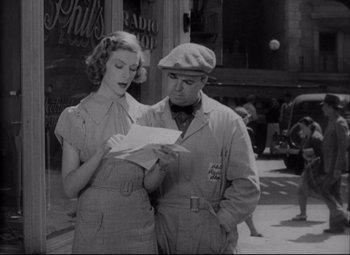 Movie still from “You Can't Take It with You” (1938), directed by Frank Capra – A man and a woman standing on a sidewalk looking at a piece of paper; Medium shot, Low angle