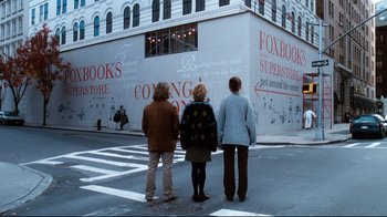 Movie still from “You've Got Mail” (1998), directed by Nora Ephron – Three people standing in front of a building on a street; Wide shot, Over the shoulder angle