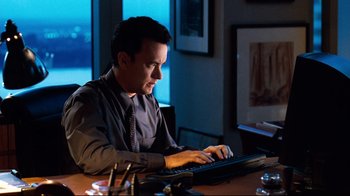 Movie still from “You've Got Mail” (1998), directed by Nora Ephron – A man sitting at a table using a computer; Medium shot, High angle