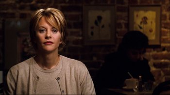 Movie still from “You've Got Mail” (1998), directed by Nora Ephron – A woman sitting in front of a brick wall in a room; Close Up shot, Over the shoulder angle