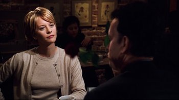 Movie still from “You've Got Mail” (1998), directed by Nora Ephron – A woman sitting at a table talking to a man in front of another man; Medium shot, Over the shoulder angle