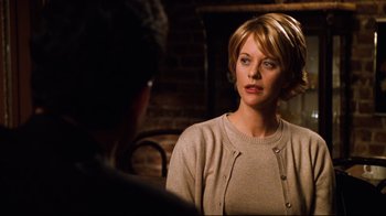 Movie still from “You've Got Mail” (1998), directed by Nora Ephron – A woman in a beige sweater talking to a man in a brown jacket; Close Up shot, Over the shoulder angle