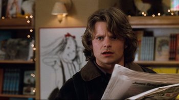Movie still from “You've Got Mail” (1998), directed by Nora Ephron – A man with long brown hair is holding papers in his hands; Close Up shot, Over the shoulder angle