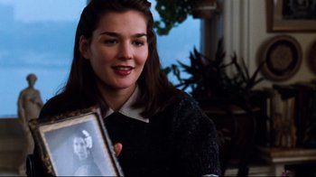Movie still from “You've Got Mail” (1998), directed by Nora Ephron – A woman holding a picture of herself in a black sweater; Close Up shot, Over the shoulder angle