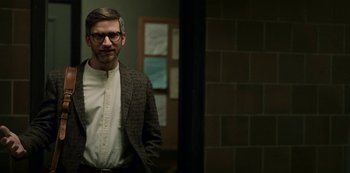 Movie still from “Archive 81” (2022), created by Rebecca Sonnenshine – A man in a suit standing in front of a brick wall; Medium shot, Over the shoulder angle