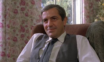 Movie still from “The Maids of Wilko” (1979), directed by Andrzej Wajda – A person sitting in a chair wearing a vest; Close Up shot, Low angle