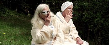 Movie still from “Youth” (2015), directed by Paolo Sorrentino – Two older women sitting on a bench smoking cigarettes; Medium shot, High angle