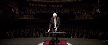 Movie still from “Youth” (2015), directed by Paolo Sorrentino – A man in a suit and white shirt standing in front of an audience; Wide shot, Low angle