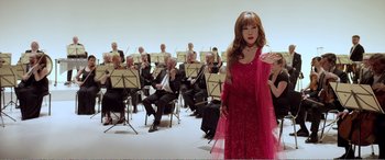 Movie still from “Youth” (2015), directed by Paolo Sorrentino – A woman in a red dress standing in front of an orchestra; Wide shot, Low angle