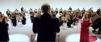 Movie still from “Youth” (2015), directed by Paolo Sorrentino – A man in a black suit is leading a orchestra; Wide shot, Low angle