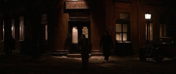 Movie still from “Youth Without Youth” (2007), directed by Francis Ford Coppola – Two people are walking in front of a building; Wide shot, Over the shoulder angle