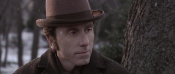 Movie still from “Youth Without Youth” (2007), directed by Francis Ford Coppola – A person wearing a hat with trees in the background; Close Up shot, Over the shoulder angle