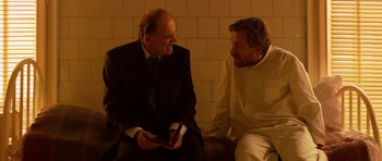 Movie still from “Youth Without Youth” (2007), directed by Francis Ford Coppola – Two men in suits are sitting next to each other; Medium shot, Over the shoulder angle