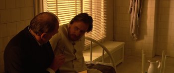 Movie still from “Youth Without Youth” (2007), directed by Francis Ford Coppola – A man sitting on a bed next to another man; Medium shot, Over the shoulder angle