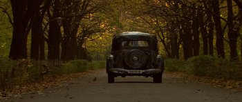 Movie still from “Youth Without Youth” (2007), directed by Francis Ford Coppola – An old car parked on the side of the road; Wide shot, High angle
