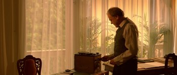 Movie still from “Youth Without Youth” (2007), directed by Francis Ford Coppola – An older man standing in front of an old radio; Medium shot, Low angle