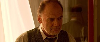 Movie still from “Youth Without Youth” (2007), directed by Francis Ford Coppola – An older man in a vest and a tie looking sad; Close Up shot, Over the shoulder angle