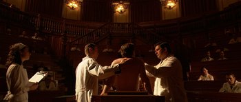 Movie still from “Youth Without Youth” (2007), directed by Francis Ford Coppola – A man is getting his chest waxed by two other men; Wide shot, Low angle