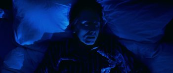 Movie still from “Youth Without Youth” (2007), directed by Francis Ford Coppola – A woman laying in a bed under a blue light; Close Up shot, Overhead angle
