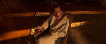 Movie still from “Youth Without Youth” (2007), directed by Francis Ford Coppola – A man sitting in a chair with a box in his hand; Medium shot, High angle