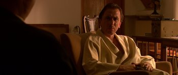 Movie still from “Youth Without Youth” (2007), directed by Francis Ford Coppola – A man sitting on a chair in a room; Medium shot, Over the shoulder angle