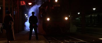 Movie still from “Youth Without Youth” (2007), directed by Francis Ford Coppola – A man standing in front of a train at night; Wide shot, Low angle