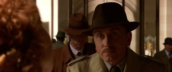 Movie still from “Youth Without Youth” (2007), directed by Francis Ford Coppola – A man wearing a hat and a trench coat; Close Up shot, Over the shoulder angle