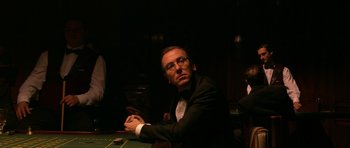Movie still from “Youth Without Youth” (2007), directed by Francis Ford Coppola – A man sitting at a table in front of cards; Medium shot, Over the shoulder angle