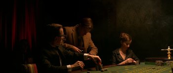 Movie still from “Youth Without Youth” (2007), directed by Francis Ford Coppola – A group of people sitting at a table playing a game; Medium shot, High angle