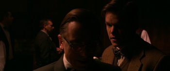 Movie still from “Youth Without Youth” (2007), directed by Francis Ford Coppola – A man in a suit smoking a cigarette next to another man in a bow tie; Close Up shot, Over the shoulder angle