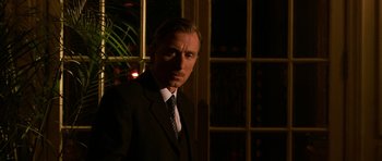 A man wearing a suit and tie standing in front of a window