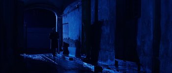 Movie still from “Youth Without Youth” (2007), directed by Francis Ford Coppola – A man standing next to a wall in a dark room; Wide shot, Over the shoulder angle