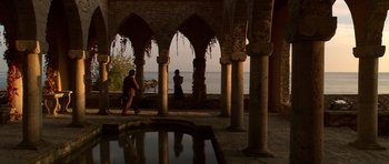 Movie still from “Youth Without Youth” (2007), directed by Francis Ford Coppola – Two people standing in a courtyard near a body of water; Extreme Wide shot, High angle