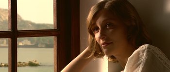 A woman sitting in front of a window with her hand behind her head
