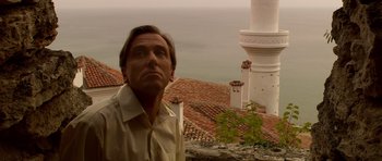 Movie still from “Youth Without Youth” (2007), directed by Francis Ford Coppola – A man standing on top of a building looking at the camera; Close Up shot, Low angle