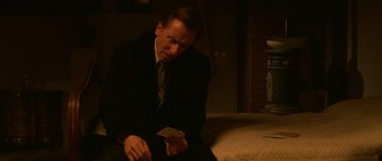 Movie still from “Youth Without Youth” (2007), directed by Francis Ford Coppola – A man sitting on a bed holding a piece of paper; Medium shot, High angle