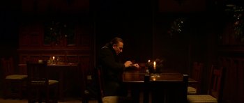 Movie still from “Youth Without Youth” (2007), directed by Francis Ford Coppola – A man sitting at a table with a lit candle in a dark room; Medium shot, High angle