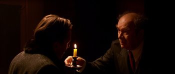 Movie still from “Youth Without Youth” (2007), directed by Francis Ford Coppola – A man holding a candle in front of another man; Close Up shot, Over the shoulder angle