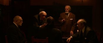Movie still from “Youth Without Youth” (2007), directed by Francis Ford Coppola – A group of men sitting around each other in a dark room; Medium shot, Over the shoulder angle