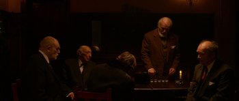 Movie still from “Youth Without Youth” (2007), directed by Francis Ford Coppola – A group of people sitting around a table; Medium shot, Over the shoulder angle