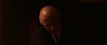 Movie still from “Youth Without Youth” (2007), directed by Francis Ford Coppola – An older man wearing a suit and tie in the dark; Close Up shot, Low angle