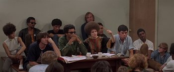Movie still from “Zabriskie Point” (1970), directed by Michelangelo Antonioni – A group of people sitting around a table; Medium shot, High angle