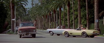 Movie still from “Zabriskie Point” (1970), directed by Michelangelo Antonioni – A car driving down a street next to palm trees; Wide shot, Low angle