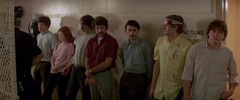Movie still from “Zabriskie Point” (1970), directed by Michelangelo Antonioni – A group of men standing next to each other in front of a wall; Medium shot, High angle