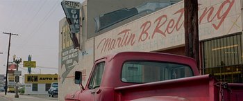Movie still from “Zabriskie Point” (1970), directed by Michelangelo Antonioni – A red truck parked in front of a building with guns painted on the side; Wide shot, Low angle