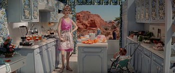 Movie still from “Zabriskie Point” (1970), directed by Michelangelo Antonioni – A woman standing in front of an island in a kitchen; Wide shot, Low angle