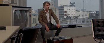 Movie still from “Zabriskie Point” (1970), directed by Michelangelo Antonioni – A man sitting on top of a chair in a room; Wide shot, Low angle