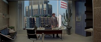 Movie still from “Zabriskie Point” (1970), directed by Michelangelo Antonioni – A man standing in front of a desk in front of an office building; Wide shot, High angle