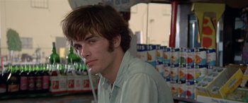 Movie still from “Zabriskie Point” (1970), directed by Michelangelo Antonioni – A young man with long brown hair is looking at the camera; Close Up shot, Low angle