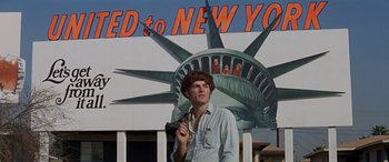 Movie still from “Zabriskie Point” (1970), directed by Michelangelo Antonioni – A man standing in front of a statue of liberty in new york; Medium shot, Low angle